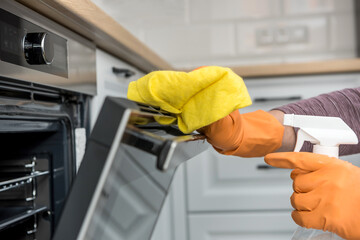 Man's hand in gloves cleaning the kitchen oven