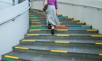 Back view of casual young woman walking up colorful spiral...
