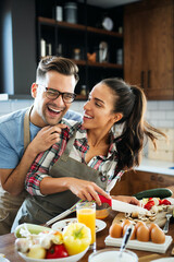 Young happy couple is enjoying and preparing healthy meal in their kitchen