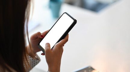 Cropped shot of woman hands are holding and touch a black cell phone with white blank screen for products display montage.