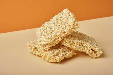 Fototapeta na wymiar three blocks of dry instant noodles on a brown and beige background