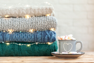 Mug filled with marshmallows against a background of folded sweaters.