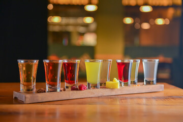 Tincture alcoholic in small shot glasses. Natural fruit alcohol drinks, shots served on a wooden...