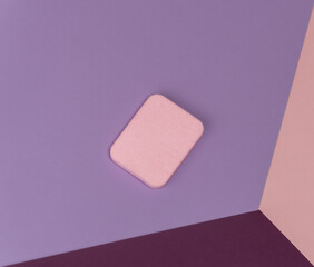 Top view of pink flat sponge on different pastel-colored backgrounds. Abstract image