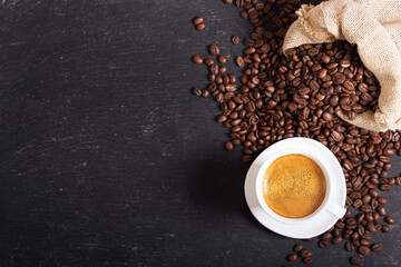 cup of coffee and coffee beans on dark background