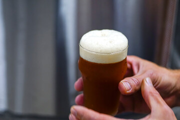 Beer mug in hand over blurred backgorund. Craft beer, making of beer. Manufacturing concept, beer plant.