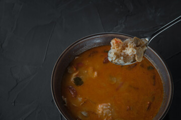 spoon with tom yam soup on the background of a plate on a stone table. Top view