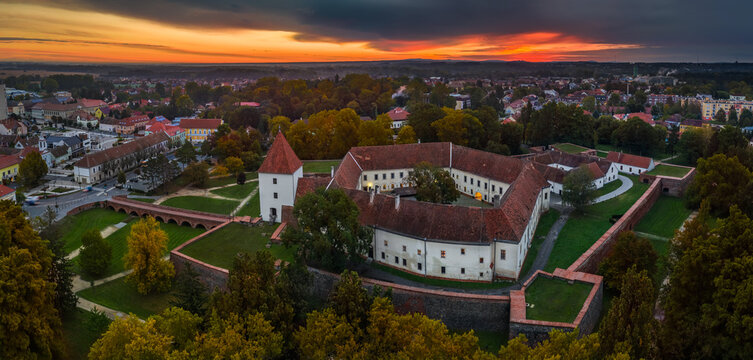 Sarvar, Hungary - Aerial panoramic view of the Castle of Sarvar (Nadasdy castle) with Sarvar Arboretum, a beautiful dramatic sunrise and rain clouds at background on a calm autumn morning