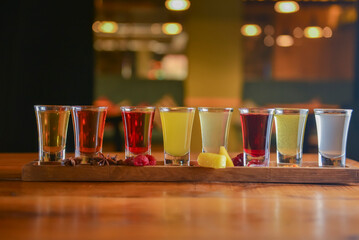 Tincture alcoholic in small shot glasses. Natural fruit alcohol drinks, shots served on a wooden table.