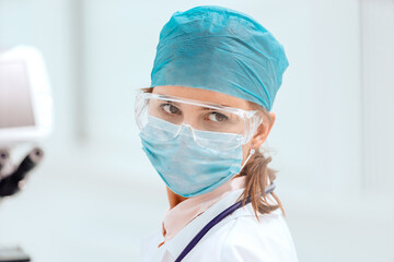 female microbiologist in a protective mask looking at you.