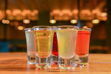 Tincture alcoholic in small shot glasses. Natural fruit alcohol drinks, shots served on a wooden table.