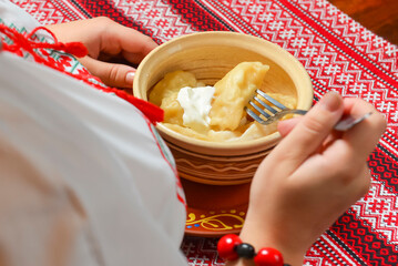 Pierogi or pyrohy, varenyky, traditional dumplings served with sour cream in bowl on wooden table.
