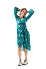 Seductive playful foxy young woman in dress messing up curly hair smiling at camera. Full body...