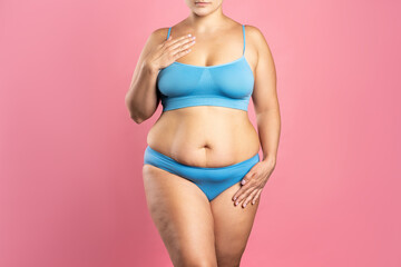 Fat woman in blue underwear on pink background, overweight female body