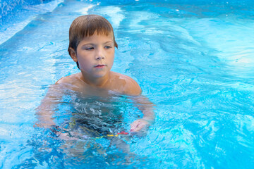 The portrait of cutest boy of six years old at swimming pool outdoor in sunny day