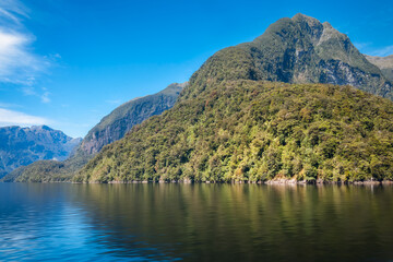 Mountain range spectacular and reflections in the water in the remote wilderness of Deep Cove at Doubtful Sound in New Zealand, South Island.