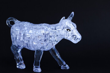 Figurine of a bull from three dimensional puzzles on black background. Symbol of coming New Year 2021, business, stock exchange, finance. Banner.