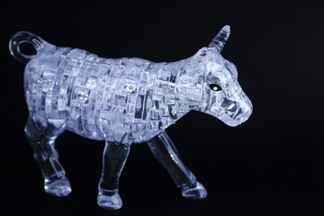 Figurine of a bull from three dimensional puzzles on black background. Symbol of coming New Year...