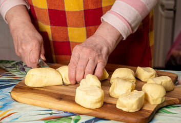 Woman cutting dough with a knife on the kitchen table. Concept of cooking dough, pizza, baking