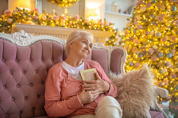 Senior woman sitting on a sofa with a photo in her hand and feeling lonely