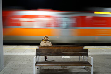 Woman sitting on a bench on the platform on train station