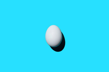 Single egg on a blue background, top view. Minimalism art photo, design, copy space. Concept for new life, Easter holiday
