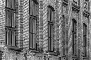 Brick building in b / w. High walls. Bare branches. University architecture. Gloomy brick house. Branches of a tree by a large window. Black dense branches in front of the window. Brick facade.