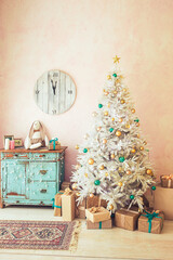 White Christmas tree and Christmas gifts in light room, turquois dresser and clock on the wall