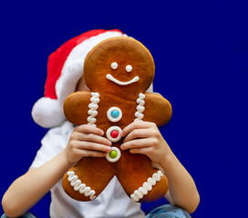 Gingerbread man in the hands of a child on a blue background. Baking, food. Christmas, new year.