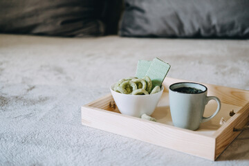 CBD Edibles, CBD-Infused Snacks, Hemp wafers with cannabis. Testy CBD Snacks in bowl and cup of herbal tea on wooden tray on the sofa at home