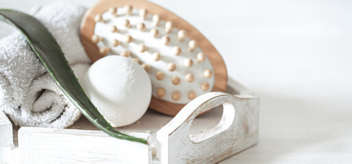 Spa composition with massage brush and bath bomb on light background close up.