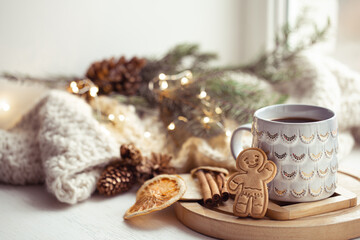 Obraz na płótnie Canvas Beautiful cup with handmade gingerbread boy on a cozy blurred background with lights.