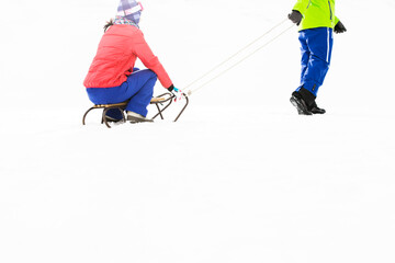 Naklejka premium Low section of young man pulling woman on sled