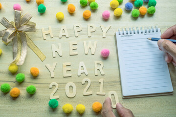 notepad with pencil, gift  and number 2021 on wood backgorund for happy new year 2021 image.For welcome new year photo.