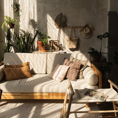 Warm boho style modern home interior design. Sofa, pillows, home plants, carpet and decorations...