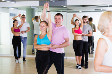 Positive men and women enjoying of partner dance in class