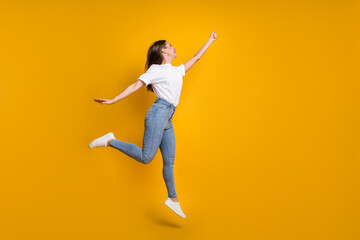 Fototapeta na wymiar Full length body size photo of carefree girl with long hair jumping keeping hand up imagine isolated on bright yellow color background
