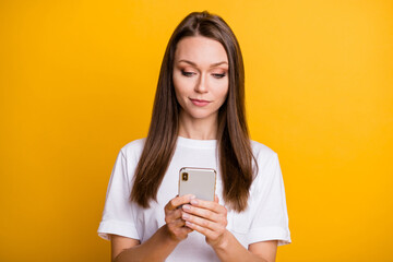 Photo portrait of calm confident female blogger using cellphone reading isolated on vivid yellow color background