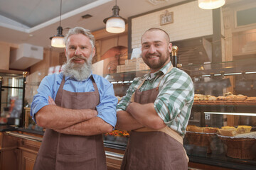 Cheerful father and son bakers enjoying working at their bakery store
