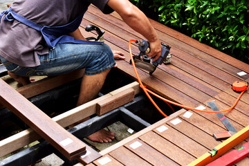 A carpenter is laying the floor with wood in the garden