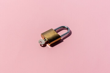 Minimal flatlay concept on pink backdrop. Single lock with key.