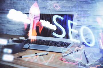 Double exposure of table with computer and seo drawing hologram. Search optimization concept.