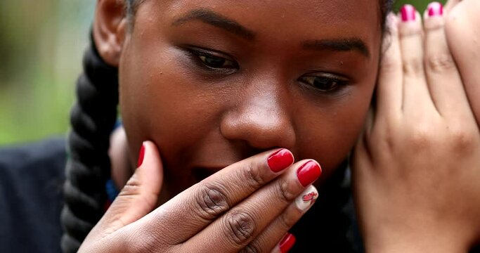 Friend reacting to shocking news, girlfriend whispering to black girl ears, sharing gossip