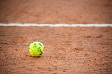Tennis ball close up on red clay courts near defocused line, competitive sport concept, no people