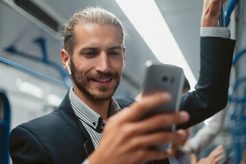 attractive man using his smartphone in subway train .