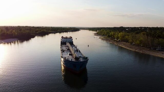 Amazing natural background with a sailing cargo ship. Footage. Aerial view of a barge flowing slowly on the backround of the endless fields and blue sky background.