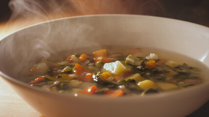 Minestrone soup dish is on table. Vegetarian healthy meal for dinner. Ready vegetable meal for lunch, hot and cozy soup for dinner at home.