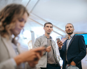 passengers with smartphones standing at the subway station .