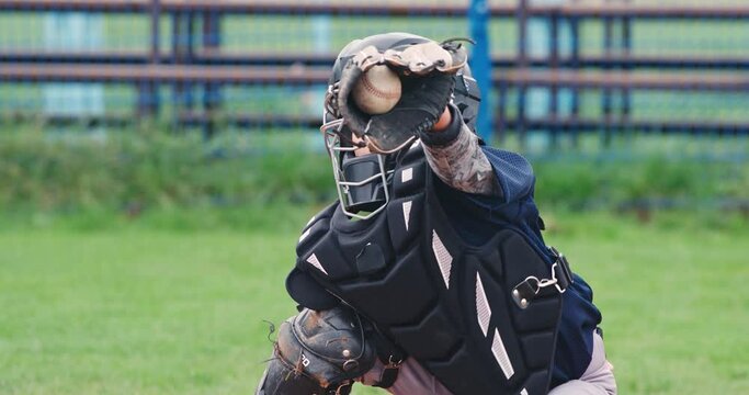 Portrait of a boy baseball player on a blurry background, the catcher in protective gear catches a flying fastball to the glove, 4k slow motion.