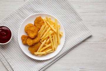 Tasty Fastfood: Chicken Nuggets and French Fries on a plate on a white wooden table, top view. Overhead, from above, flat lay. Copy space.